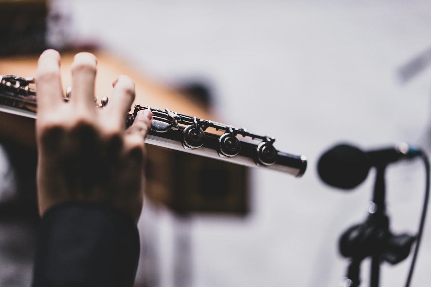 Hands pressing keys on a silver flute during practice.
